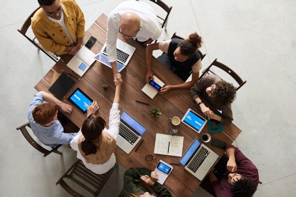 pexels-photo-3183197 Top view of a diverse team collaborating in an office setting with laptops and tablets, promoting cooperation.