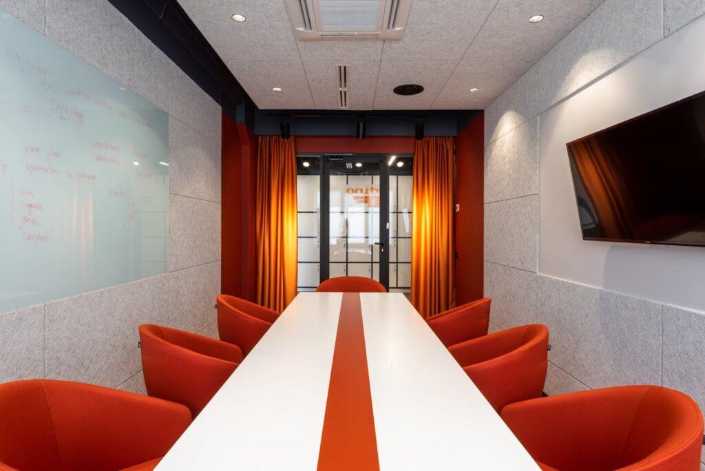 pexels-photo-6794971 Elegant and colorful conference room with orange chairs and modern decor.