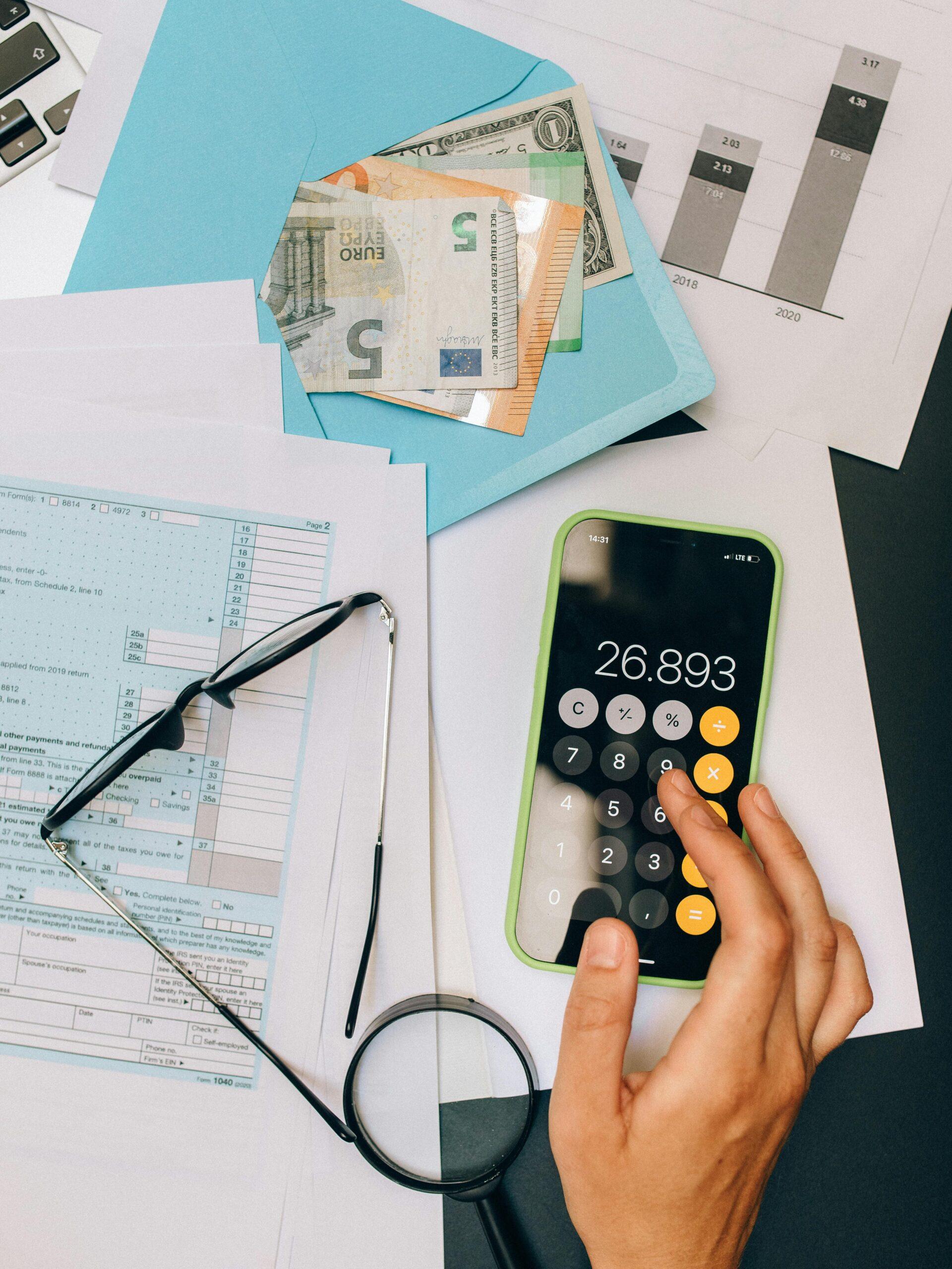 A top view of financial documents, calculator on smartphone, and euro notes, depicting business analysis.